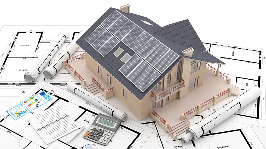 A model of a house with solar panels on the roof is placed on architectural blueprints. Rolls of blueprints are scattered around, accompanied by a notebook, a pen, and a calculator.